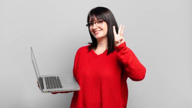 Artı güzel bir kadın gülümsüyor ve arkadaş canlısı görünüyor, üç ya da üç numarayı gösteriyor, eli önde, geriye doğru sayıyor.