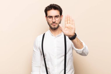 Genç ve yakışıklı adam ciddi, sert, hoşnutsuz ve kızgın görünüyor.