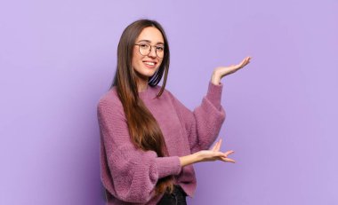 Genç, hoş, sıradan bir kadın gururla ve güvenle gülümsüyor, mutlu ve tatmin olmuş hissediyor ve fotokopi alanında bir konsept gösteriyor.