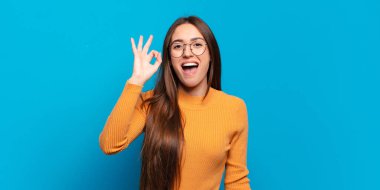 Genç, hoş, sıradan bir kadın kendini başarılı ve tatmin olmuş hissediyor ağzı açık gülümsüyor, elle imza atıyor.