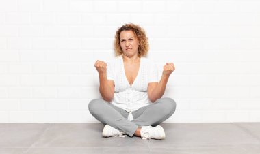 Orta yaşlı kadın kışkırtıcı, agresif ve müstehcen hissediyor. İsyankar bir tavırla orta parmağını hareket ettiriyor.