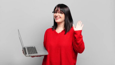 Artı boyut olarak güzel bir kadın mutlu ve neşeyle gülümsüyor, el sallıyor, seni selamlıyor ve selamlıyor, ya da hoşça kal diyor.