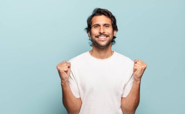 Genç yakışıklı Hintli adam şok olmuş, heyecanlı ve mutlu hissediyor, gülüyor ve başarıyı kutluyor,!