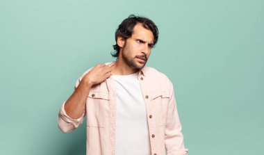 Genç, yakışıklı Hintli bir adam stresli, endişeli, yorgun ve hayal kırıklığına uğramış, gömleğini çekiştirip duruyor.