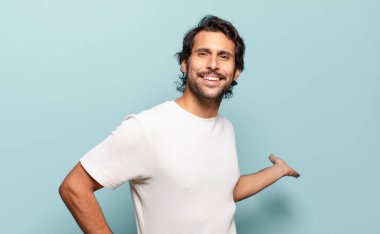 Genç, yakışıklı Hintli adam kendini mutlu ve neşeli hissediyor, gülümsüyor ve seni selamlıyor, dostça bir jestle içeri davet ediyor.