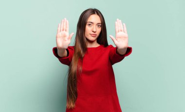 Genç, hoş, sıradan bir kadın ciddi, mutsuz, kızgın ve hoşnutsuz görünüyor. Girmeyi yasaklıyor ya da her iki avuçta da dur diyor.