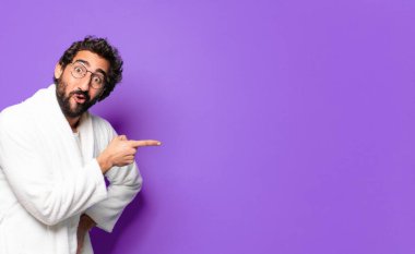 Bornoz giyip evde uyanan çılgın sakallı genç adam.