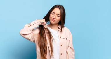 Genç, hoş, sıradan bir kadın stresli, endişeli, yorgun ve hayal kırıklığına uğramış, gömleğini çekiştirmiş, sorunlardan bıkmış görünüyor.