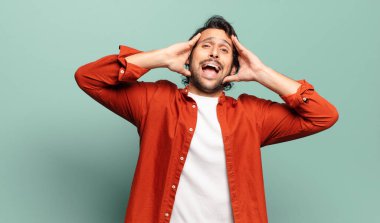 Genç, yakışıklı Hintli adam el ele tutuşuyor, ağzı açık, son derece şanslı, şaşkın, heyecanlı ve mutlu hissediyor.