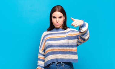 Kızgın, çılgın bir patrona benzeyen sinirli bir ifadeyle kameraya bakan genç, hoş, sıradan bir kadın.