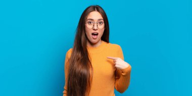 Şok olmuş ve ağzı açık, kendini işaret eden genç, hoş, sıradan bir kadın.