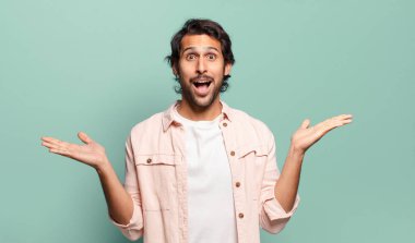 Genç, yakışıklı Hintli adam mutlu, heyecanlı, şaşırmış ya da şok olmuş, gülümseyen ve hayrete düşmüş hissediyor.