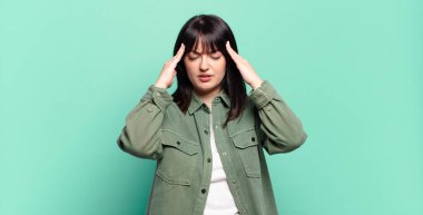 Artı boyut olarak güzel bir kadın stresli ve hayal kırıklığına uğramış görünüyor, baskı altında çalışıyor ve başı ağrıyor.