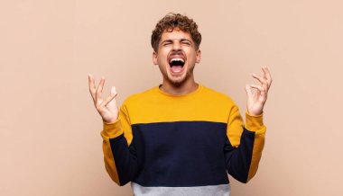 Genç adam öfkeyle bağırıyor, stresli hissediyor ve ellerini havaya kaldırıp neden ben diye bağırıyor.