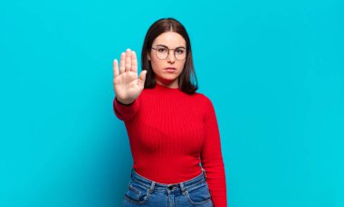 Genç, hoş, sıradan bir kadın ciddi, sert, hoşnutsuz ve kızgın görünüyor.