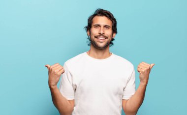 Genç ve yakışıklı Hintli adam neşeyle gülümsüyor ve mutlu görünüyor, kaygısız ve pozitif hissediyor.