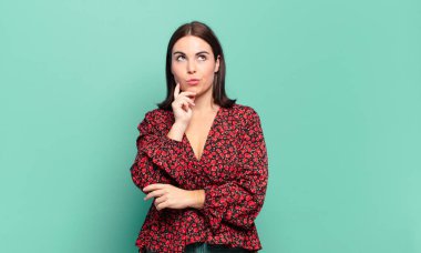 Genç, sıradan, düşünceli, kuşkulu ve kafası karışık, farklı seçenekleri olan, hangi kararı vereceğini merak eden bir kadın.