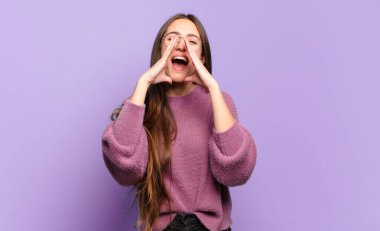 Genç, hoş, sıradan bir kadın. Mutlu, heyecanlı ve pozitif hissediyor. Elleri ağızda, bağırıyor.