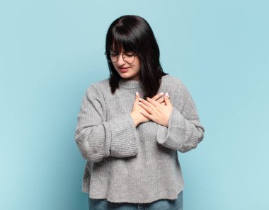 Artı, üzgün, yaralı ve kalbi kırık görünen, iki elini de kalbe yakın tutan, ağlayan ve depresyonda hisseden boyunda güzel bir kadın.