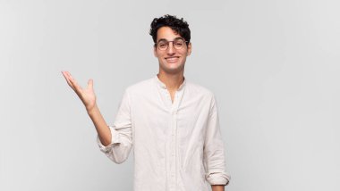 Genç yakışıklı adam kendini mutlu, şaşırmış ve neşeli hissediyor. Pozitif bir tavırla gülümsüyor. Bir çözüm ya da fikir buluyor.