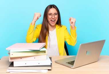 Genç ve güzel iş kadını mutlu, pozitif ve başarılı hissediyor, zaferi, başarıları veya iyi şansı kutluyor.