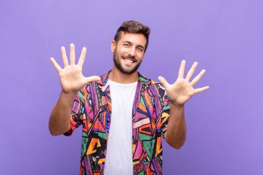 Genç adam gülümsüyor ve arkadaş canlısı görünüyor, onuncu ya da onuncu numarayı gösteriyor, eli önde, geri sayıyor.