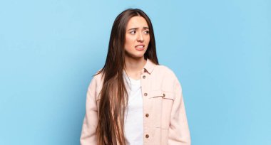 Endişeli, stresli, endişeli, korkmuş, panikleyen ve dişlerini sıkan genç, hoş, sıradan bir kadın.