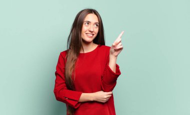 Genç, güzel, sıradan bir kadın mutlu bir şekilde gülümsüyor ve yan bakıyor, merak ediyor, düşünüyor ya da bir fikri var.