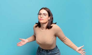 young pretty casual woman feeling clueless and confused, having no idea, absolutely puzzled with a dumb or foolish look