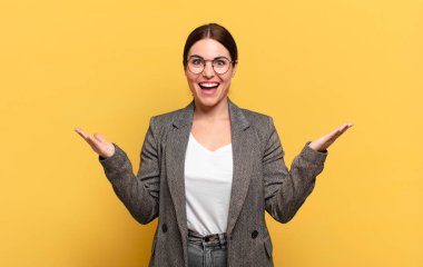 Genç, güzel bir kadın mutlu, heyecanlı, şaşırmış ya da şaşırmış hissediyor. İnanılmaz bir şeye gülümsüyor ve hayrete düşüyor.