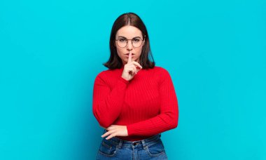 Genç, hoş, sıradan bir kadın ciddi görünüyor ve parmaklarını dudaklarına bastırıp sessizlik ya da sessizlik talep ediyor, sır saklıyor.