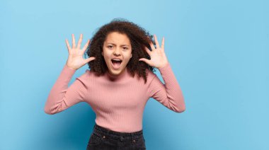 Panik ya da öfke içinde çığlık atan kız, şok olmuş, korkmuş ya da öfkeli, elleri başının yanında.