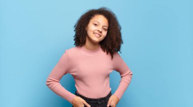 Neşeli, mutlu, kendinden emin ve rahat bir ifadeyle gülümseyen bir kız.