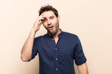 Genç yakışıklı adam mutlu, şaşkın ve şaşırmış görünüyor, gülümsüyor ve inanılmaz ve inanılmaz iyi haberleri fark ediyor.