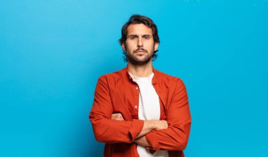 Genç, yakışıklı Hintli adam hayal kırıklığına uğramış ve hayal kırıklığına uğramış hissediyor. Ciddi görünüyor, kızgın ve kollarını kavuşturmuş.