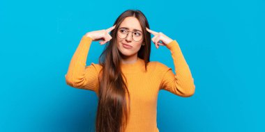 Genç, hoş, sıradan bir kadın. Konsantre olmuş ve bir fikir üzerinde kafa yoruyor. Bir soruna ya da soruna çözüm bulmayı hayal ediyor.