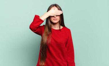 Genç, hoş, sıradan bir kadın. Tek eliyle gözlerini kapatıyor. Korkmuş, endişeli, merak ediyor ya da körü körüne bir sürpriz bekliyor.