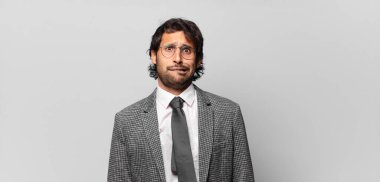 Genç, yakışıklı Hintli bir adam kafası karışmış ve kafası karışmış görünüyor. Gergin bir hareketle dudağını ısırıyor. Sorunun cevabını bilmiyor. iş kavramı