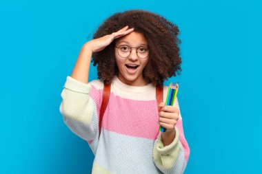 Oldukça afro bir genç mutlu, şaşkın ve şaşırmış görünüyor, gülümsüyor ve inanılmaz ve inanılmaz iyi haberleri fark ediyor. öğrenci konsepti