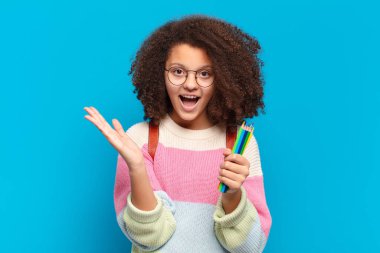 Oldukça afro bir genç mutlu, heyecanlı, şaşırmış ya da şok olmuş hissediyor, gülümsüyor ve inanılmaz bir şeye şaşırıyor. öğrenci konsepti