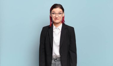 Genç ve çekici kızıl saçlı kadın kafası karışmış görünüyor, gergin bir hareketle dudaklarını ısırıyor, sorunun cevabını bilmiyor.