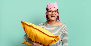 Genç ve çekici kızıl saçlı kadın mutlu ve hoş bir şekilde şaşırmış görünüyor. Büyülenmiş ve şok olmuş bir ifadeyle heyecanlanıyor ve pijama giyiyor..