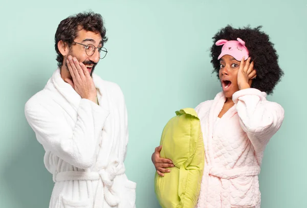 幸せを感じ 興奮し 驚きを感じる友人の多人種のカップルは 顔に両手で側に探している パジャマと家のコンセプト — ストック写真
