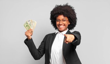 Genç afro iş kadını kameraya tatmin olmuş, kendinden emin, dostane bir gülümsemeyle bakıyor ve seni seçiyor. iş kavramı