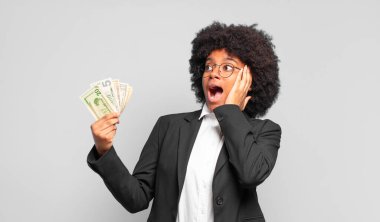 Genç afro iş kadını mutlu, heyecanlı ve şaşırmış hissediyor, iki eli yüzü üzerinde yana bakıyor. iş kavramı