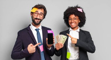 Genç iş adamları neşeli bir şekilde gülümsüyor, mutlu hissediyorlar ve kenarı ve yukarıyı gösteriyorlar, kopyalama alanında nesneler gösteriyorlar. mizahi iş konsepti