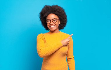  Neşeli bir şekilde gülümseyen, mutlu hisseden, kenarı ve yukarıyı gösteren, kopya uzayda nesneleri gösteren