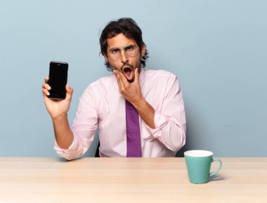 Genç ve yakışıklı Hintli bir adam ağzı ve gözleri sonuna kadar açık ve eli çenesinde, hoş olmayan bir şokta, ne ya da vay canına diyor. iş kavramı