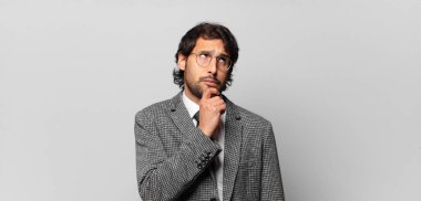 Genç, yakışıklı Hintli adam düşünüyor, kuşkulu ve şaşkın hissediyor, farklı seçenekleri var, hangi kararı vereceğini merak ediyor. iş kavramı