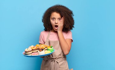 Oldukça afro bir genç şokta ve korkmuş, ağzı açık ve elleri yanaklarında korkmuş görünüyor. Komik fırıncı konsepti